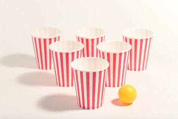 Striped paper cups and ball on white background. Minimalism concept