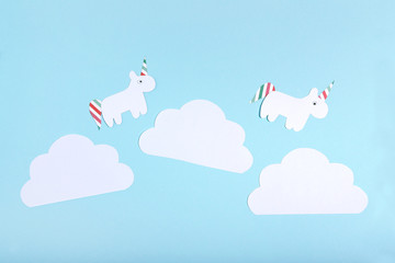 Paper unicorns and clouds on blue background. Minimalism concept