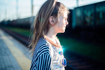 Portrait of a beautiful little girl waiting for a train at the station