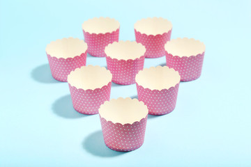 Pink cupcake cases on blue background. Minimalism concept
