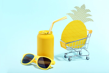 Aluminum can sunglasses and paper pineapple in shopping cart on blue background. Minimalism concept