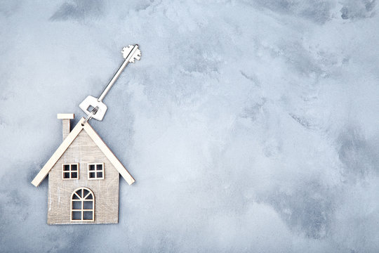 Silver key with house symbol on grey background