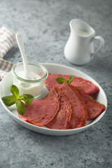 Homemade beetroot crepes with cream