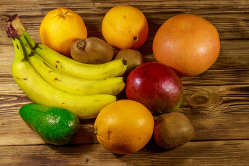 Assortment of tropical fruits on wooden table. Still life with bananas, mango, oranges, avocado, grapefruit and kiwi fruits
