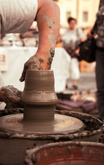 Hands of a potter shaping a clay pot on a potter wheel