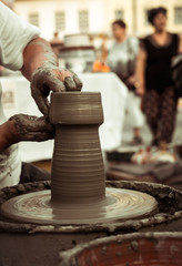 Hands of a potter shaping a clay pot on a potter wheel