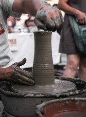 Hands of a potter shaping a clay pot on a potter wheel