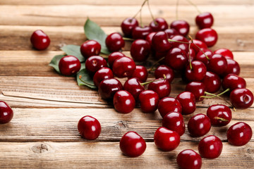 Sweet cherries with leafs on brown wooden table