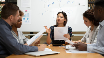 Female asian executive discuss paperwork with diverse partners at meeting