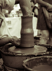 Hands of a potter shaping a clay pot on a potter wheel
