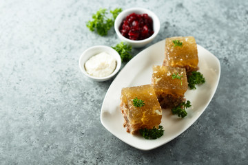Festive meat jelly with sauces on white plate