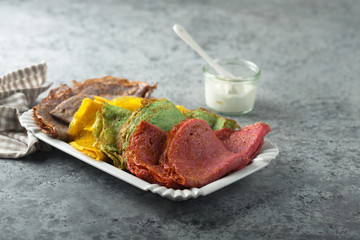 Homemade rainbow pancakes on a white plate