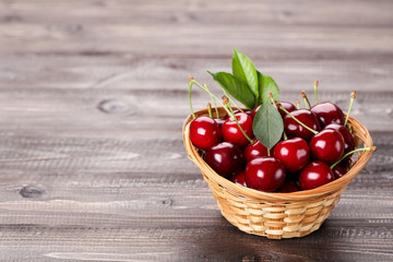 Sweet cherries with basket on wooden table