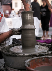 Hands of a potter shaping a clay pot on a potter wheel