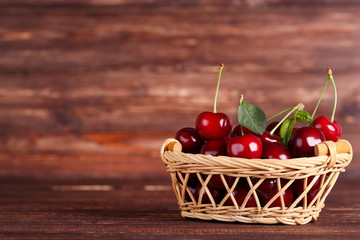 Sweet cherries in basket on brown wooden table