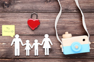 Family figures with padlock heart and wooden camera on brown wooden background
