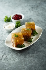 Festive meat jelly with sauces on white plate