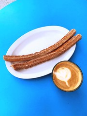 Fried cinnamon churros on plate with latte.