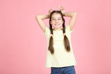 Beautiful young girl showing ears by hands on pink background