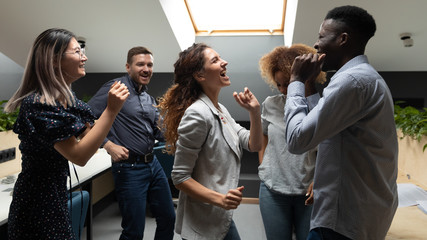 Overjoyed carefree multiracial business team dancing together in office