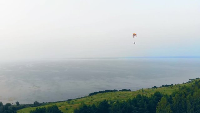 An athlete training with a glider high in sky.