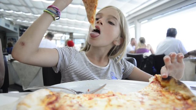Adorable kid girl eating pizza in italian restaurant