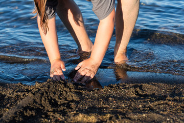 Child building troughs and trenches around their sand castle