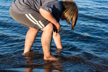 Child digging on the beach in the water
