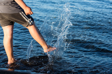 Child kicks the water splashing the lake