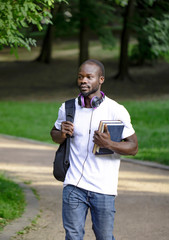 Young enthusiastic African male student walking through campus park