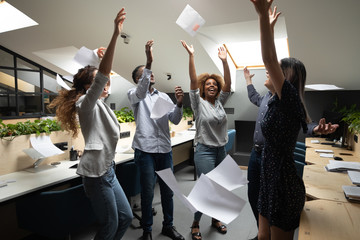 Happy multiethnic business team throwing tossing papers in office