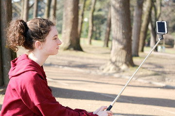 Obraz premium teenager girl making photo with selfie stick outside near lake