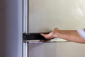 Abstract female hand of woman is opening a gray refrigerator door