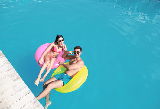 Woman in bikini with boyfriend swimming at resort. Happy young couple - Powered by Adobe