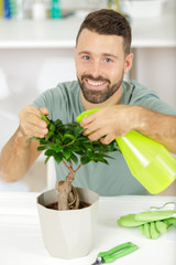 male gardener sprays a bonsai