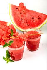 Watermelon smoothie fresh juice with mint, pieces of watermelon in the shape of hearts and slices of watermelon. Healthy drinks in glasses on a white background.