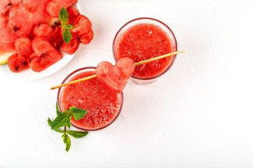 Watermelon smoothie fresh juice with mint, pieces of watermelon in the shape of hearts and slices of watermelon. Healthy drinks in glasses on a white background.