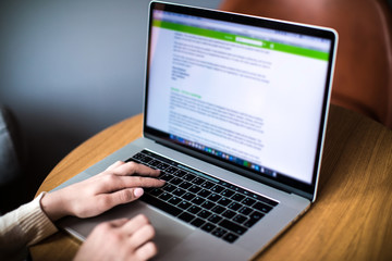 Woman project manager searching information on web site via laptop computer while sitting in office.Female experienced business plan writer  keyboarding on notebook.Student learning online via netbook