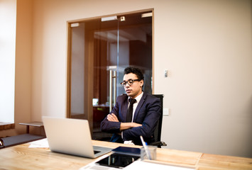 Confident business man having video conference via laptop computer with international partners while sitting in office. Male lawyer reading information on netbook. CEO having online call on notebook