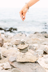 hand placing pebble of a stone tower on the sea side 