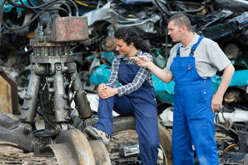 workers looking at grabber in scrap metal yard