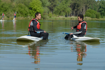 Fototapeta na wymiar men talking while sitting on their paddleboard