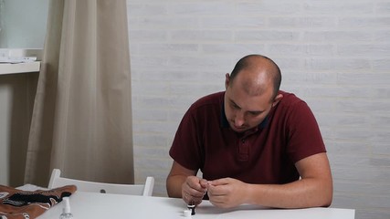 A respectable bald man treats his nails with a special drug in order to cure the fungus. Hand fungus treatment at home