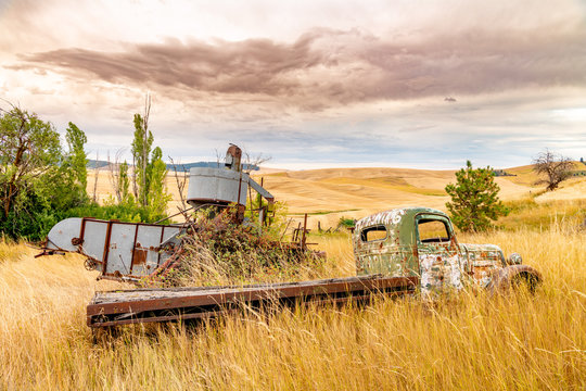 Old farm truck with No Hunting painted on and rolling wheat fields during harvest