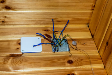 Electric cables stick out from electrical panel on house wooden wall