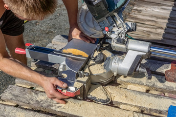 A carpenter saws off a board with circular saw