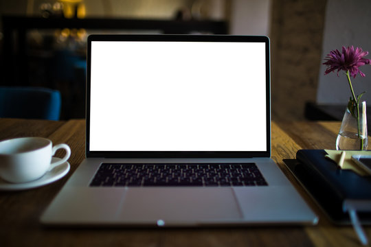 Open laptop computer with empty copy space screen background for promotional content lying on a table in coffee shop interior. Modern portable net-book with blank monitor for advertising text message