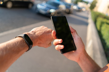 guy look at a smartphone and a fitness bracelet on his hand. black mockup screens