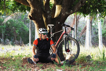 A cyclist resting in the evening at sunset under a tree.
