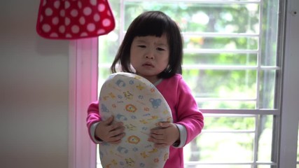 The little Asian girl very angry and upset, frowning her brow and showing a tongue. Bad mannered little girl  Crying in bed room